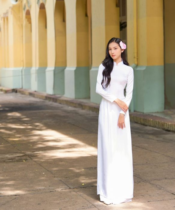 Người mẫu mặc áo dài lụa trắng đứng trước dãy hành lang cổ kính, phong cách truyền thống tinh khôi